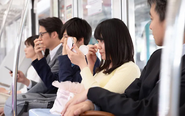 une femme se maquille dans le train au japon